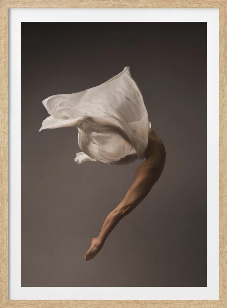 A minimalist fine art photograph of a dancer in mid-air against a solid grey background. The dancer's body is arched backwards, with a large piece of flowing white fabric enveloping their torso and creating a sense of dynamic, weightless motion. Only their muscular leg and pointed foot are clearly visible, emphasizing grace and form. Wall Art