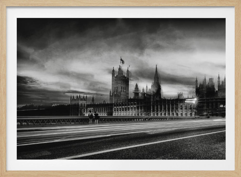 A framed, black and white long-exposure photograph of the Houses of Parliament and Big Ben in London. The view is from a bridge, with streaks of white light from traffic blurring across the road in the foreground under a dramatic, cloudy sky. Wall Art