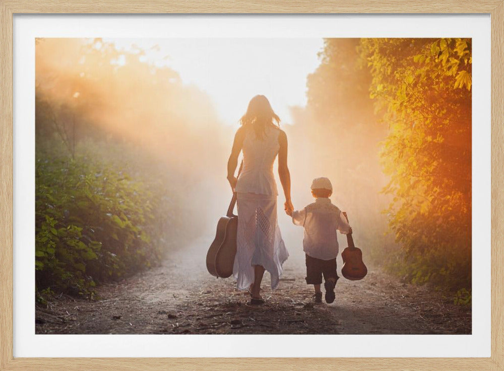 A woman and a young boy seen from behind, walking hand-in-hand down a sunlit dirt path through a forest. The woman carries a guitar and the boy carries a smaller one, both silhouetted against a warm, hazy sunset. Print