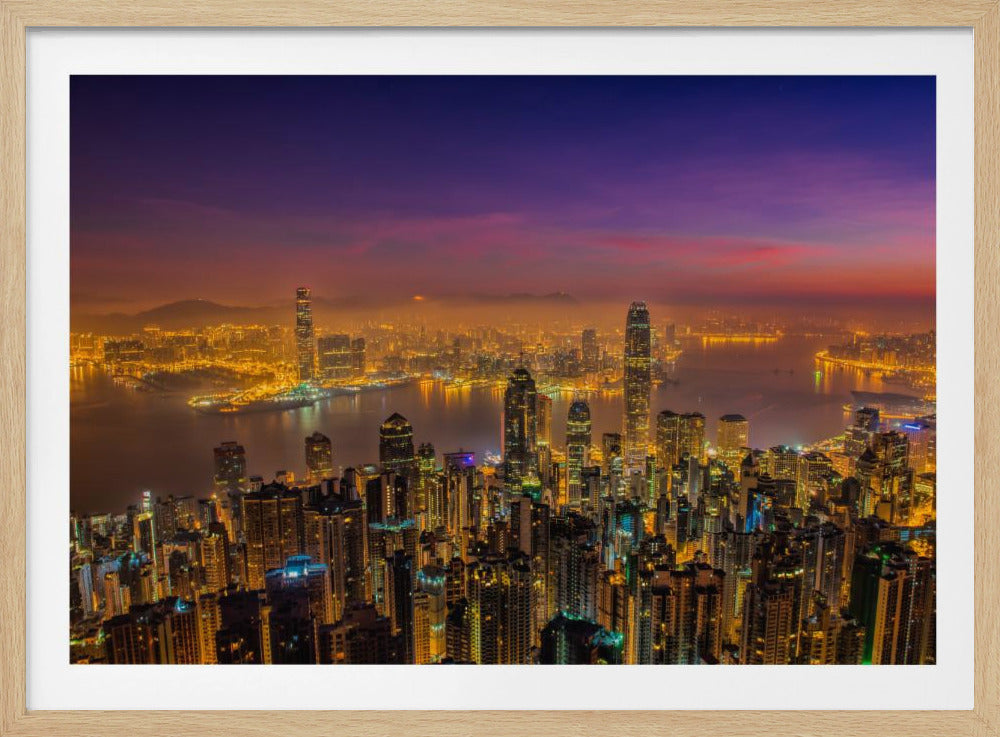 A breathtaking aerial photograph of a bustling city skyline at dusk, encased in a silver frame. The sky transitions from a deep purple to a warm orange, while the city's numerous skyscrapers are illuminated with bright yellow lights that reflect off the water of a large harbor. Poster