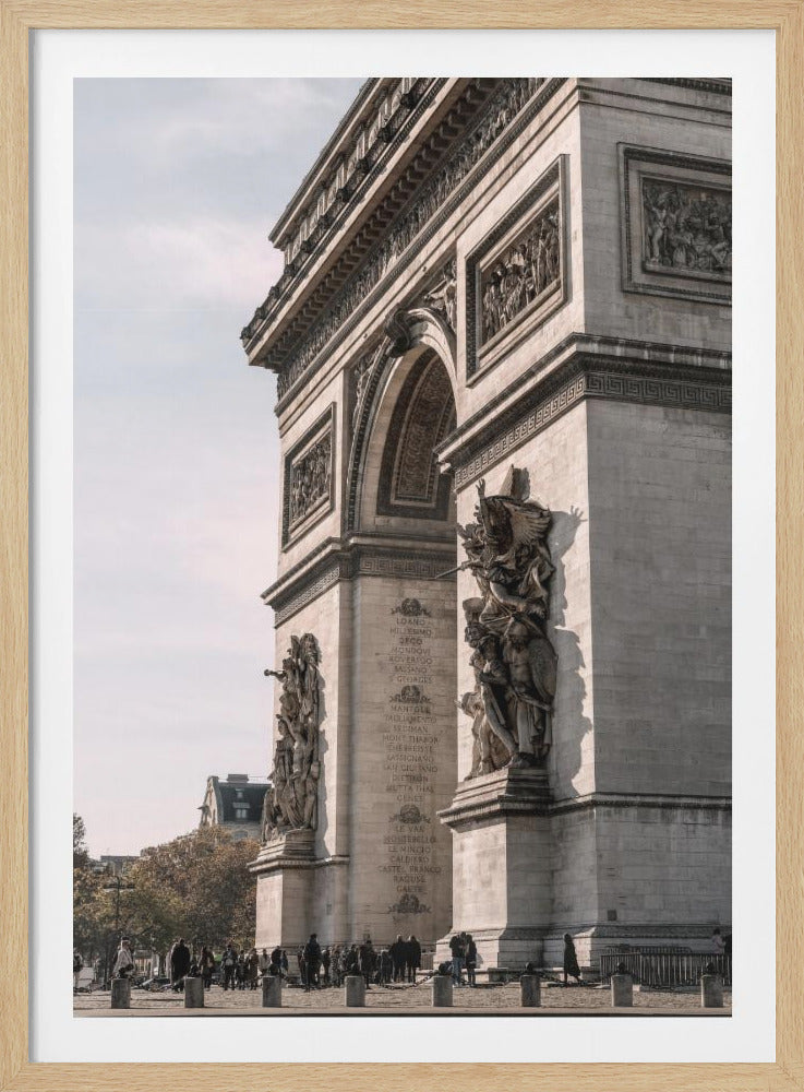 A low-angle, side-view photograph of the Arc de Triomphe in Paris, highlighting its detailed stone carvings and sculptures against a pale sky, all enclosed in a thin black frame. Print
