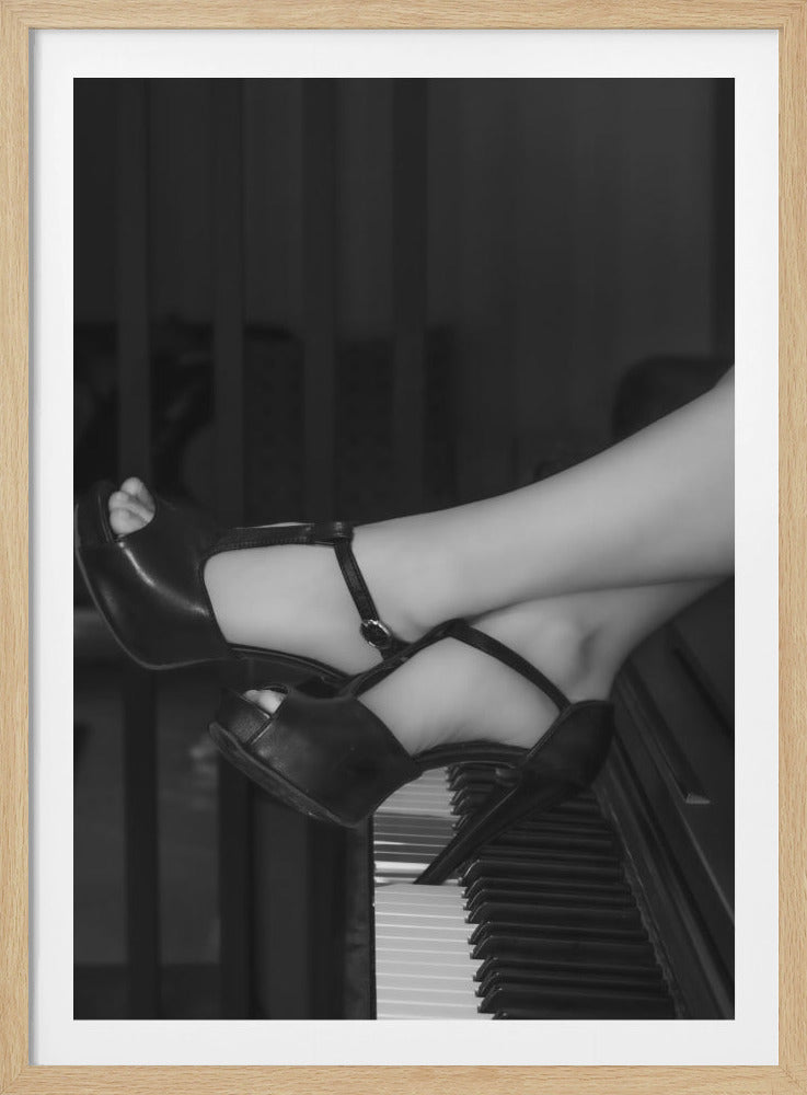 A black and white photograph showing a close-up of a person's legs and feet in black platform high heels, resting elegantly on the keys of a piano. The feet are crossed, and the heel of one shoe presses down on the keyboard. Print