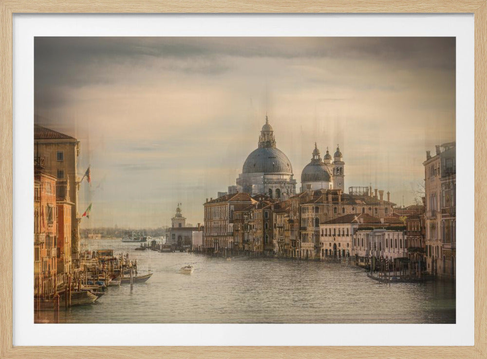 A scenic, warm-toned photograph of the Grand Canal in Venice, Italy, with the iconic domes of the Basilica di Santa Maria della Salute in the background. Historic buildings and boats line the waterway under a hazy, golden sky, all framed by a brushed silver border. Artwork