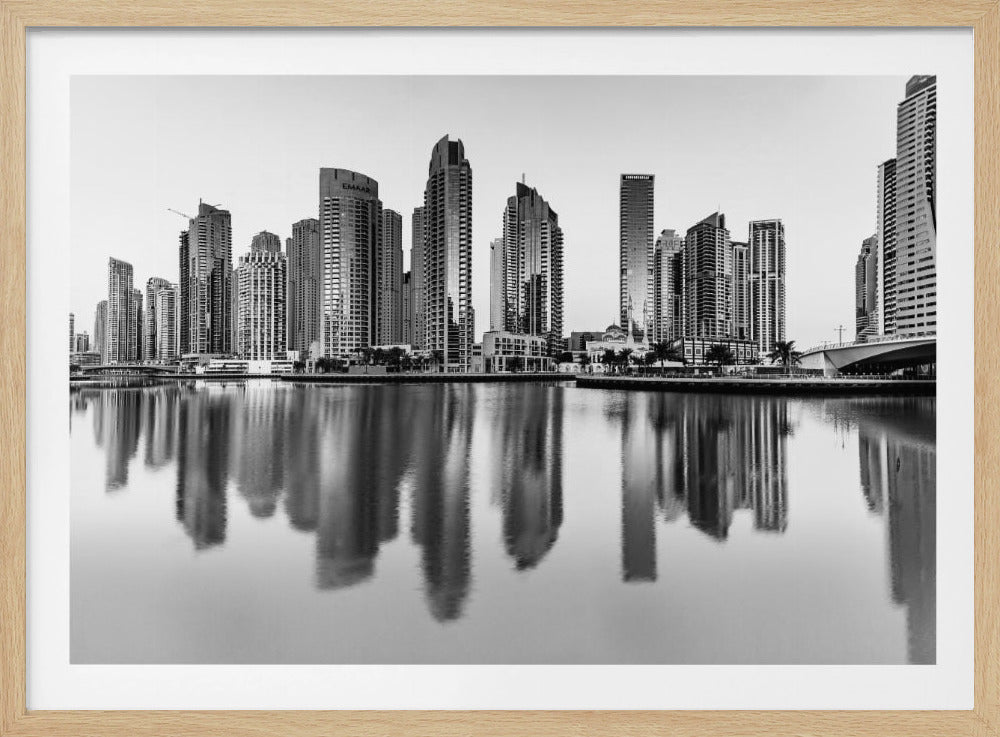 A framed black and white photograph of the Dubai Marina skyline, with its modern skyscrapers perfectly reflected in the calm water of the canal. Decor