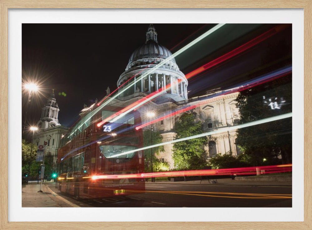 A long-exposure night photograph of a red double-decker bus in London, creating vibrant red and white light trails in front of the illuminated St. Paul's Cathedral. Decor