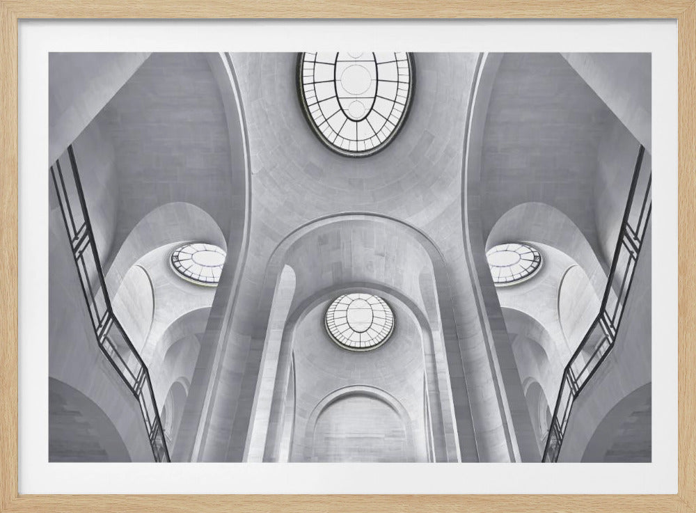 A framed, black and white photograph looking up at the complex architectural ceiling of a grand hall. The symmetrical view showcases a series of soaring stone arches, vaulted ceilings, and large, oval-shaped windows that create a dramatic play of light and shadow. Print