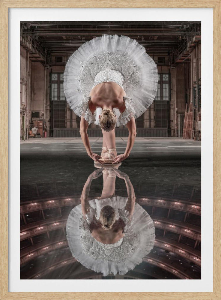 A ballerina in a white tutu bends forward on a highly reflective stage. Her reflection reveals an audience in a grand theater, contrasting with the actual backstage setting visible behind her. Wall Art