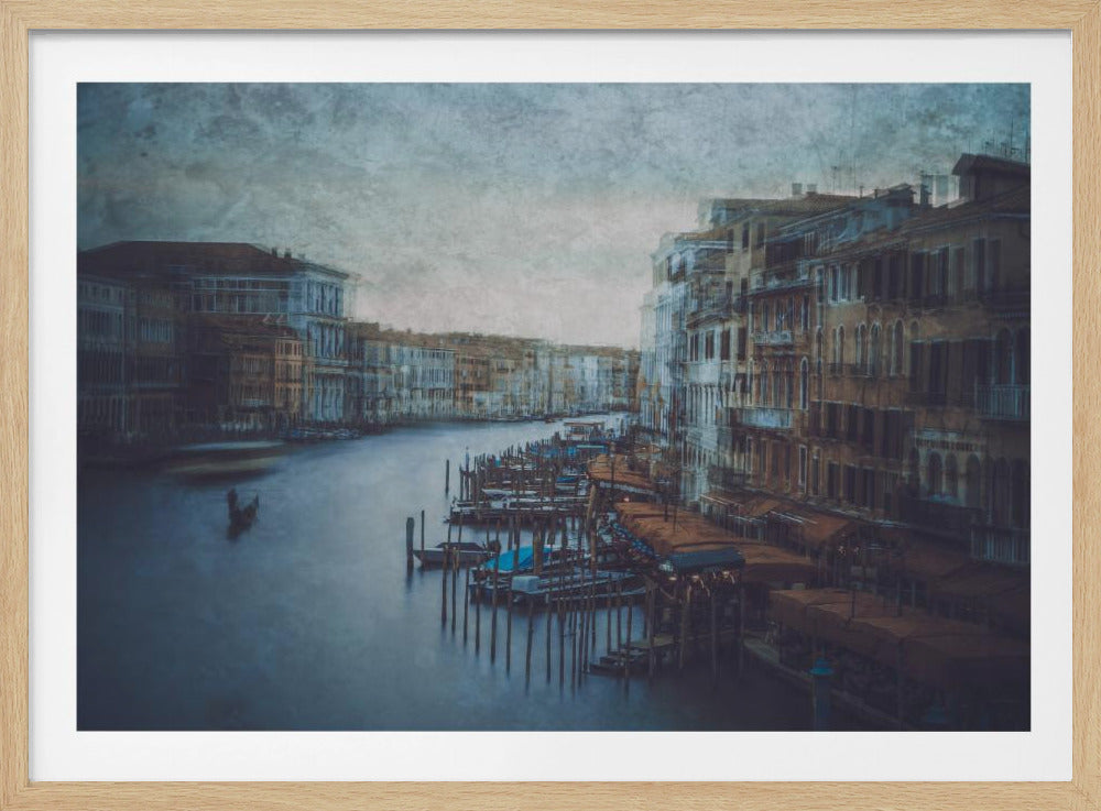 A moody, artistic long-exposure photograph of the Grand Canal in Venice, Italy, presented in a silver frame. The water is a smooth, deep blue, reflecting the historic, multi-story buildings that line the canal. Docked boats and a lone gondola add to the classic Venetian scene, all rendered in a desaturated, textured style that gives the image a timeless, ethereal quality. Print