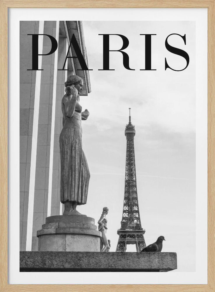 A black and white travel poster for Paris, featuring a large classical statue of a woman in the foreground, with the Eiffel Tower visible in the distance under a cloudy sky. The word 'PARIS' is written in a large, elegant serif font across the top of the image. A pigeon is perched on a ledge in the lower right corner. Decor