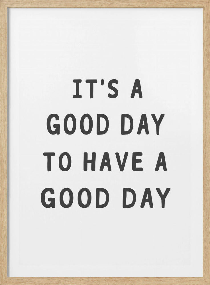 A framed black and white art print with the phrase 'IT'S A GOOD DAY TO HAVE A GOOD DAY' in a bold, dark gray, sans-serif font. Artwork