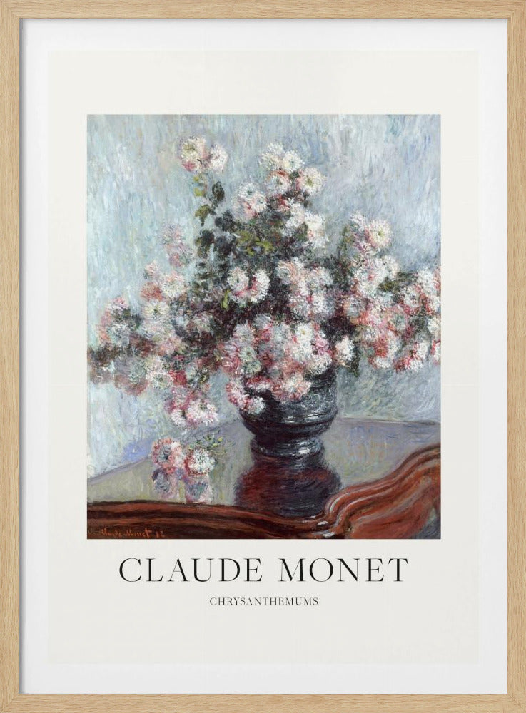 A framed art print of Claude Monet's impressionist painting, 'Chrysanthemums.' The painting features a lush bouquet of pink and white chrysanthemums in a dark vase resting on a reflective, mahogany-colored table against a light blue, textured background. The print includes a white border with the artist's name and the title below the artwork, all enclosed in a simple black frame. Print