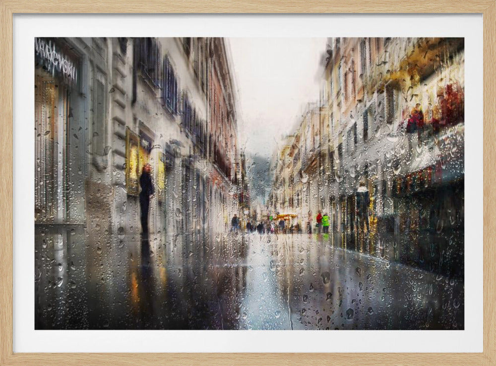 An impressionistic painting of a city street on a rainy day, viewed as if through a window covered in water droplets. The scene is blurred and atmospheric, with the wet pavement reflecting the muted colors of the buildings and distant figures. The artwork is presented in a silver frame. Decor