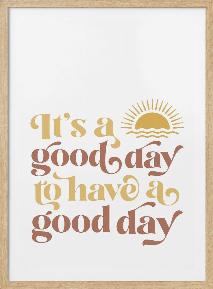 A framed art print with a white background featuring the quote 'It's a good day to have a good day' in a retro, curvy font. The text color alternates between terracotta brown and mustard yellow. Above the text is a small yellow icon of a sun rising over waves. Wall Art