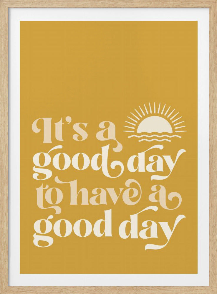 A framed poster with a mustard yellow background featuring the inspirational quote 'It's a good day to have a good day' in a stylish, retro cream-colored font. A small icon of a sun rising over the ocean is next to the text. Poster