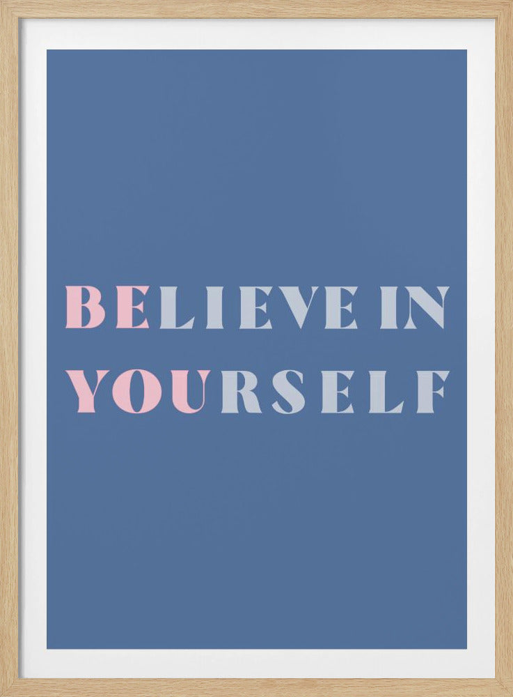 A motivational art print with a slate blue background and a thin black frame. The words 'BELIEVE IN YOURSELF' are centered in a serif font, with the words 'BELIEVE' and 'YOURSELF' featuring an alternating color pattern of light pink and light grey. Artwork