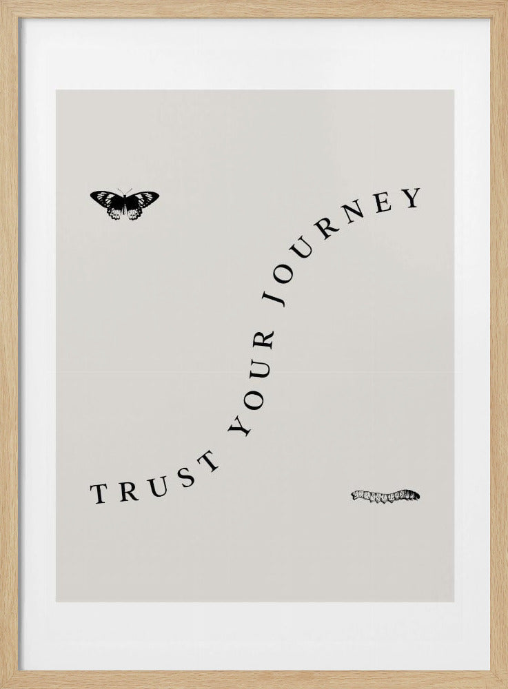 A minimalist art print with a black frame featuring the words 'TRUST YOUR JOURNEY' in a black serif font, curving upwards from left to right on a light beige background. A small black caterpillar is positioned below the text on the right, and a black butterfly is above the text on the left, symbolizing transformation. Wall Art