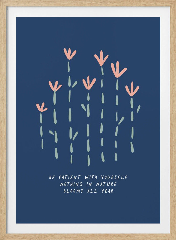 An inspirational art print with a dark blue background featuring stylized pink flowers with light green dashed stems. Below the flowers, the text reads 'Be patient with yourself, nothing in nature blooms all year' in a white, handwritten font. The art is shown in a simple black frame. Poster