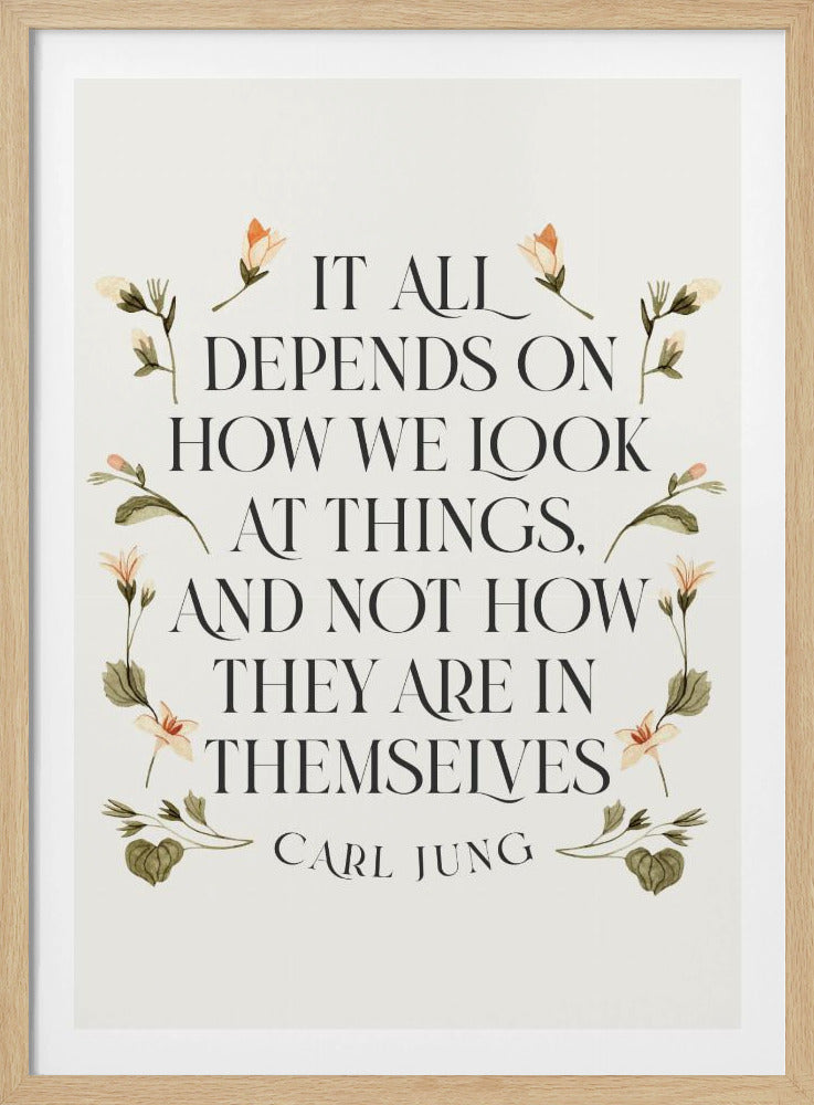 A framed art print featuring an inspirational quote by Carl Jung. The text reads 'It all depends on how we look at things, and not how they are in themselves' in a black serif font against an off-white background. The quote is encircled by a delicate wreath of watercolor botanicals with green leaves and pale orange flowers. Poster