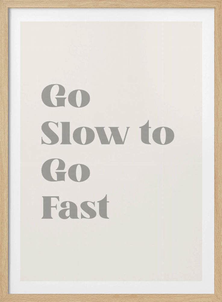 A minimalist framed poster featuring a thin black frame and an off-white background. The motivational phrase 'Go Slow to Go Fast' is printed in a bold, grey serif font, with the words stacked vertically in the center. Print