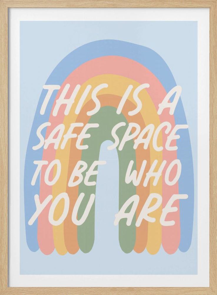 A framed art print with a muted pastel rainbow on a light blue background. Overlaid in a white, handwritten font is the text, 'THIS IS A SAFE SPACE TO BE WHO YOU ARE'. Wall Art
