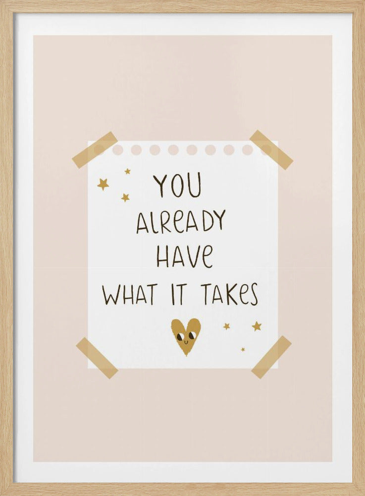 A motivational poster in a black frame with a pale pink background. A white piece of notebook paper is taped to the center with the handwritten text 'YOU ALREADY HAVE WHAT IT TAKES' in brown. It's decorated with small gold stars and a cute, smiling gold heart. Decor