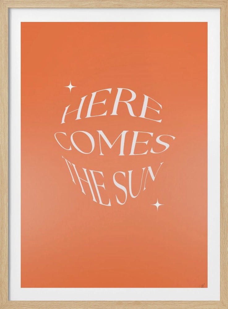 A framed art print with a warm orange background. The words 'HERE COMES THE SUN' are in the center in a stylized, wavy white font, giving a sense of warmth and movement. Two small white sparkles are also on the print. Poster