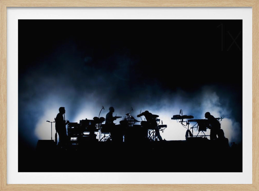 A dramatic silhouette of a band performing on a dark stage, backlit by bright white and blue lights that illuminate clouds of smoke behind them. Artwork