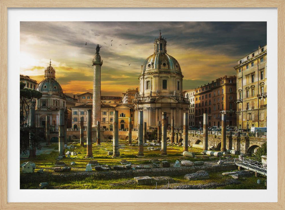 A framed photograph of Trajan's Forum in Rome, Italy, during a dramatic sunset. The foreground is filled with ancient stone columns and ruins on a grassy field, leading to the prominent Trajan's Column and the domed Church of the Most Holy Name of Mary against a golden and dark cloudy sky. Wall Art