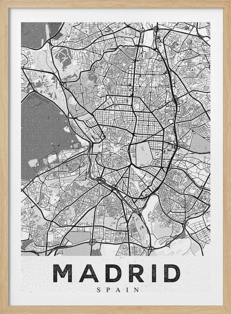 A framed, minimalist black and white map of Madrid. The map shows a detailed network of roads and city blocks. Major roads are depicted as thick black lines, while smaller streets are thinner. Parks and bodies of water are filled with shades of gray texture. At the bottom, the word 'MADRID' is printed in large, bold, black capital letters on a textured white background. Artwork