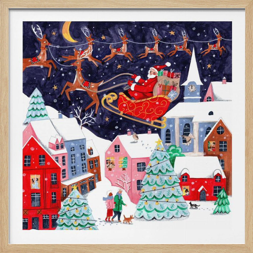 A festive illustration of Santa Claus flying in his sleigh pulled by reindeer over a snowy European-style village at night. The sky is a deep starry blue with a crescent moon, and the houses below are painted in vibrant reds, pinks, and blues, with warm light in the windows. People walk in the snow near decorated Christmas trees. Decor