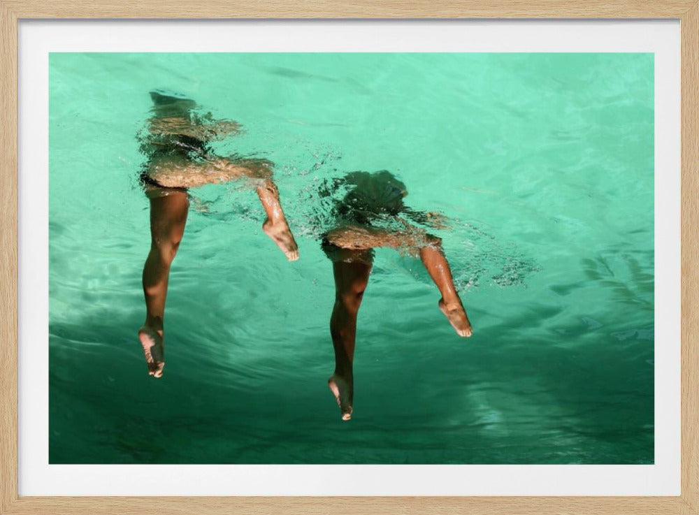 An underwater photograph of the lower bodies of two people swimming in bright turquoise water, their legs and feet dangling below the rippling surface. Poster