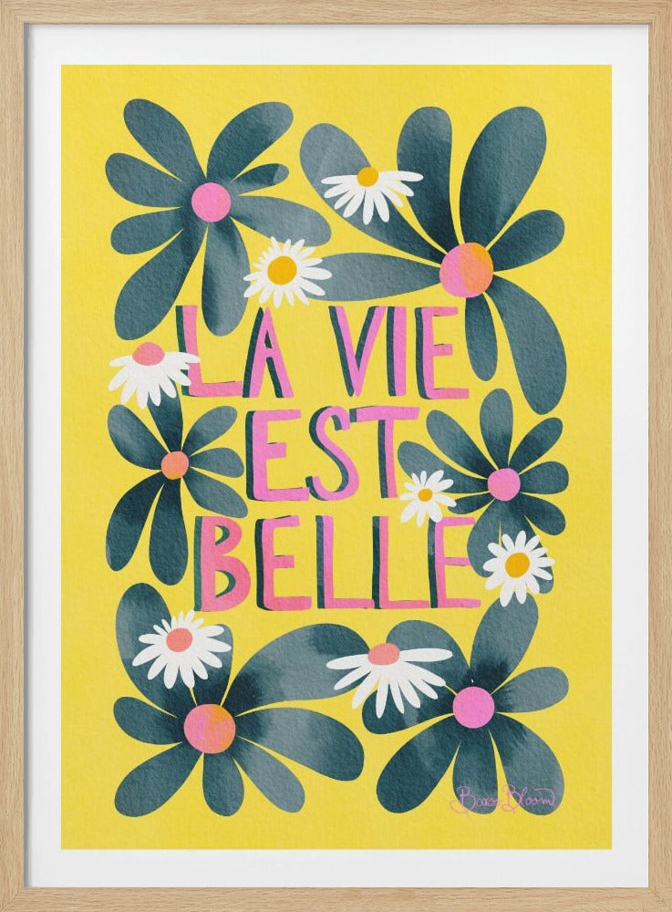 A cheerful art print with a bright yellow background featuring the French phrase 'La Vie Est Belle' in stylized pink letters. The text is surrounded by large, dark teal flowers with pink centers and smaller white daisies. Wall Art