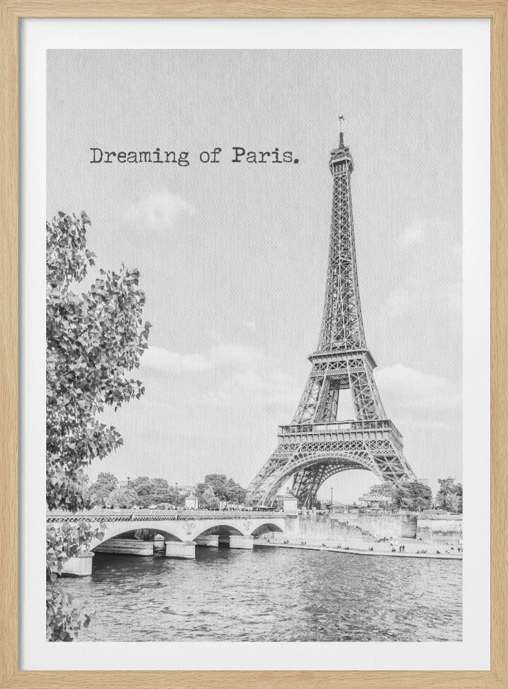 A black and white framed artwork featuring a classic view of the Eiffel Tower in Paris. The scene includes the Pont d'Iéna bridge over the Seine river in the foreground. In the top left corner, the text 'Dreaming of Paris.' is written in a typewriter font. Decor