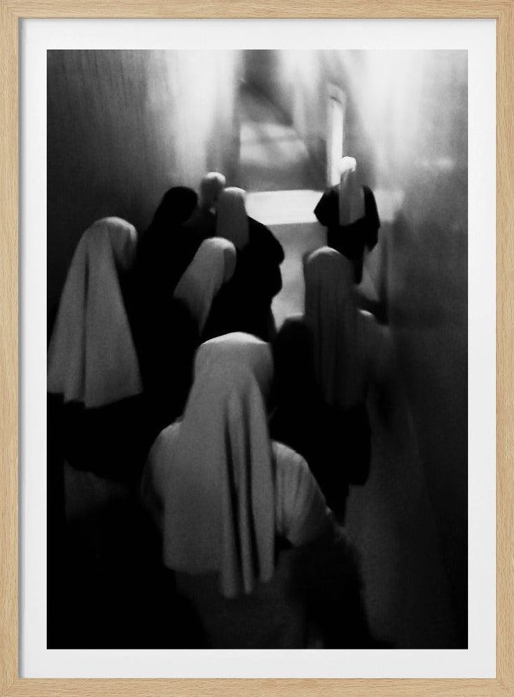 A mysterious black and white photograph captures a group of robed figures, possibly nuns, from above as they walk down a dark, narrow corridor. The image is blurred, creating a ghostly, ethereal atmosphere as the figures' white head coverings stand out against the deep shadows. Artwork