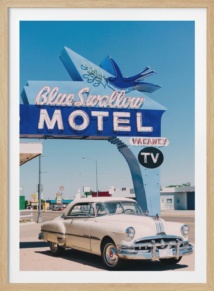 A classic cream-colored Pontiac car is parked in front of the large, blue neon sign for the Blue Swallow Motel. The sign features a blue swallow bird and white lettering against a bright blue sky, creating a nostalgic, mid-century American roadside scene. Poster