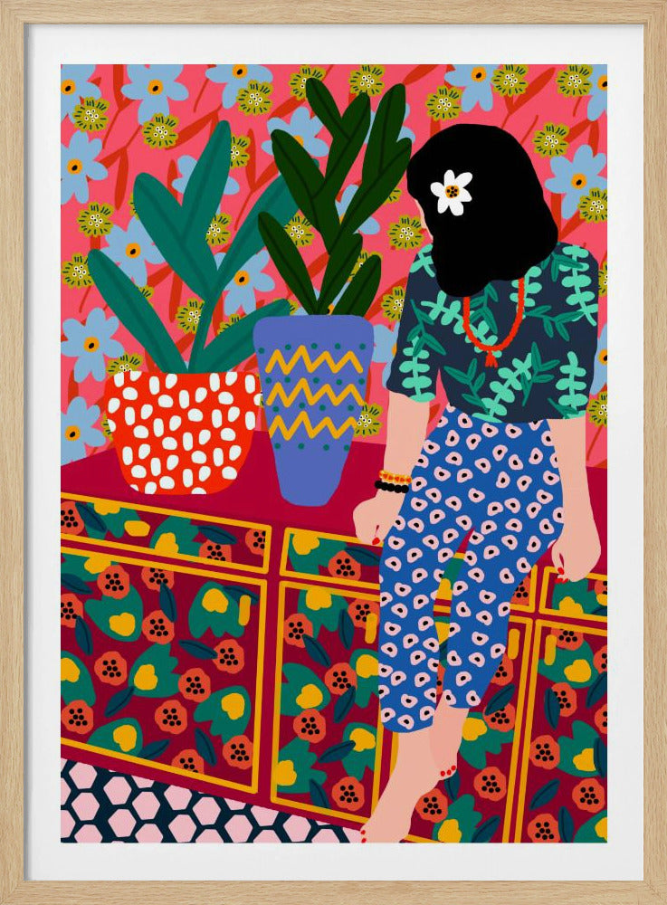A colorful, maximalist illustration of a woman with black hair and a flower, sitting on a patterned cabinet. She wears a dark blue shirt with green leaves and blue pants with white circles. Next to her are two potted plants in brightly patterned pots, set against a pink and blue floral wallpaper. Poster