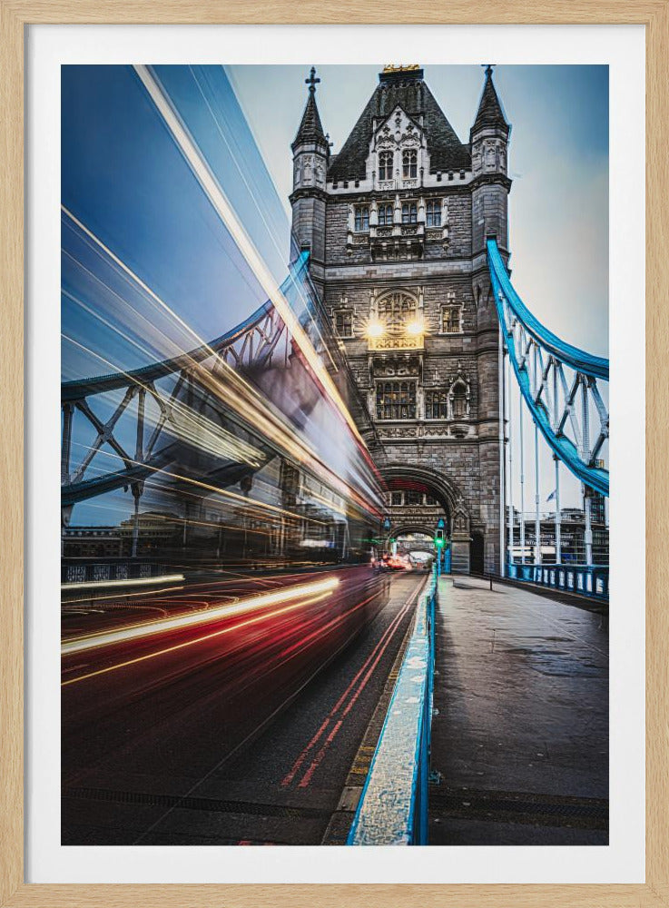 A dynamic long-exposure photograph of London's Tower Bridge, featuring a speeding double-decker bus that creates vibrant red and white light trails, juxtaposed against the historic stone architecture of the bridge's tower. Decor