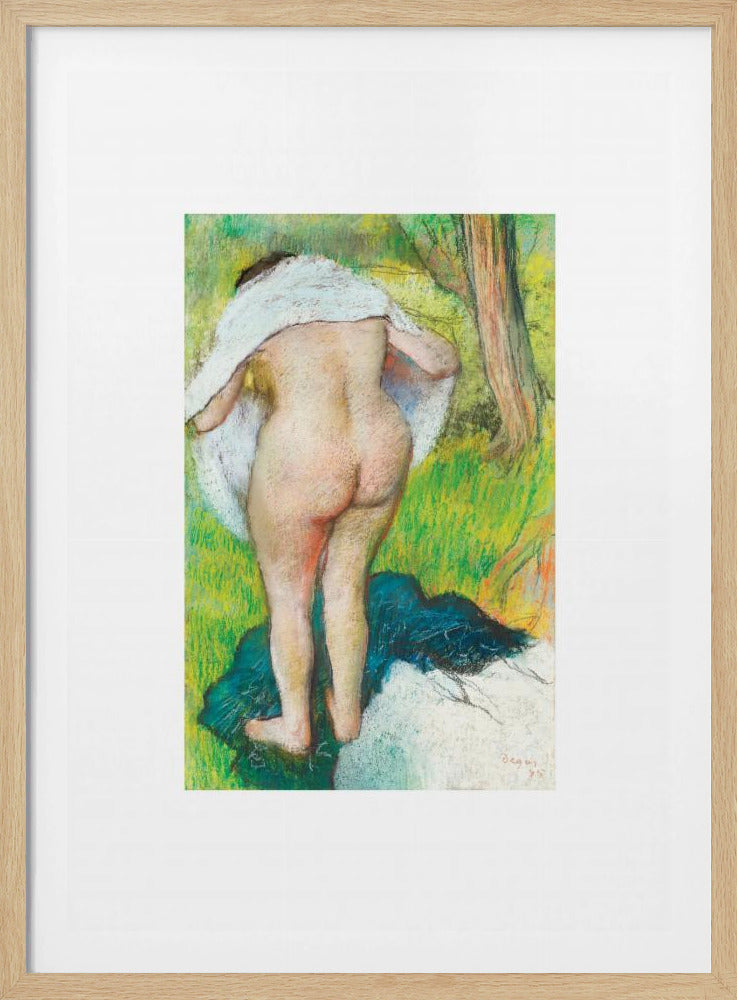 A framed pastel artwork by Edgar Degas showing the back of a nude woman as she dries herself with a white towel in a lush green landscape. The impressionist style is evident in the soft, textured application of color. Artwork