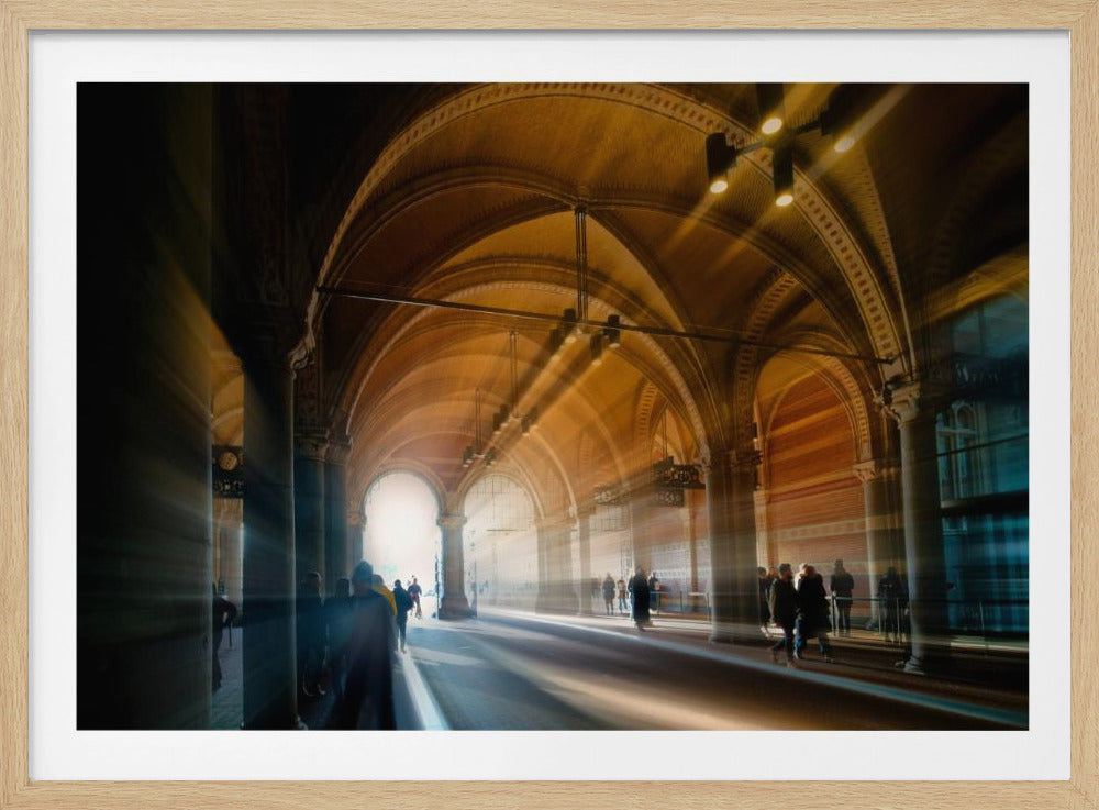 A long exposure photograph of a grand, vaulted hallway with brick arches. Dramatic beams of golden light cut through the space, creating horizontal streaks and a motion blur effect. Silhouettes of people walk through the atmospheric light and shadow. Wall Art
