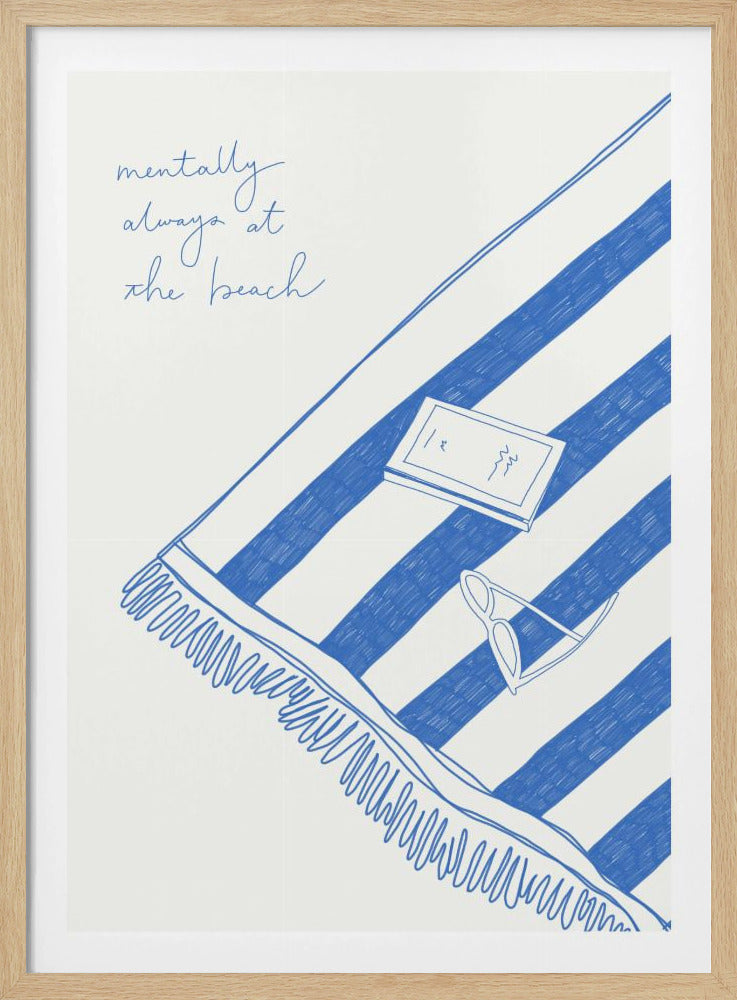 A framed piece of art featuring a blue line drawing on a white background. The drawing shows a blue and white striped beach towel with a book and sunglasses resting on it. In the top left corner, the text 'mentally always at the beach' is written in blue script. Wall Art