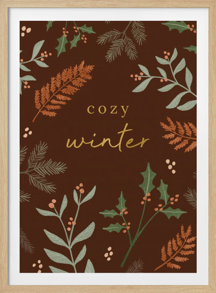 A warm, illustrative poster with a dark brown background featuring the words 'cozy winter' in gold script at the center. The text is framed by a wreath of winter botanicals, including holly, pine needles, and ferns in shades of green and burnt orange. Print