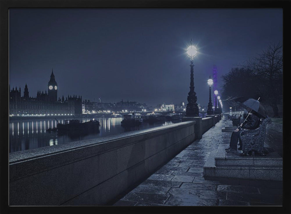 A moody, blue-toned night photograph of London. A solitary figure sits on a bench under an umbrella on a wet stone walkway along the River Thames, illuminated by vintage streetlights. Across the river, the iconic Houses of Parliament and Big Ben are lit up against the dark sky, their lights reflecting in the water. Poster