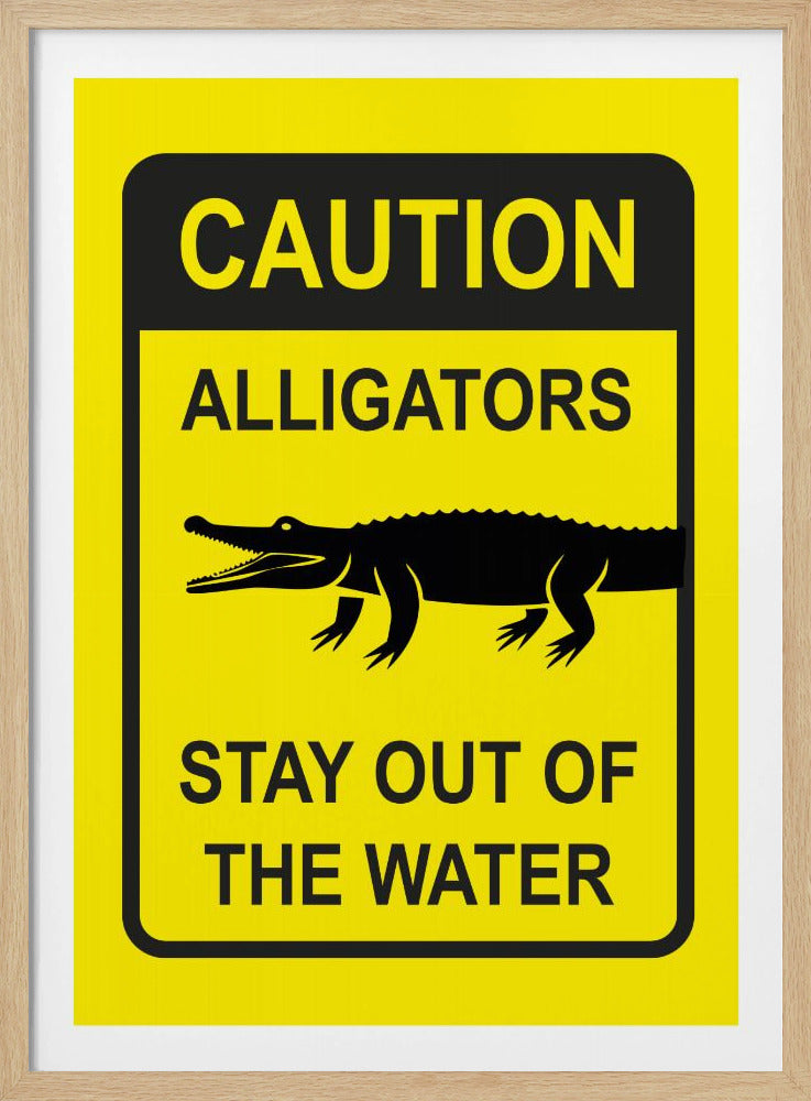 A yellow and black rectangular warning sign in a black frame. The sign reads 'CAUTION ALLIGATORS' at the top, features a black silhouette of an alligator in the center, and says 'STAY OUT OF THE WATER' at the bottom. Decor