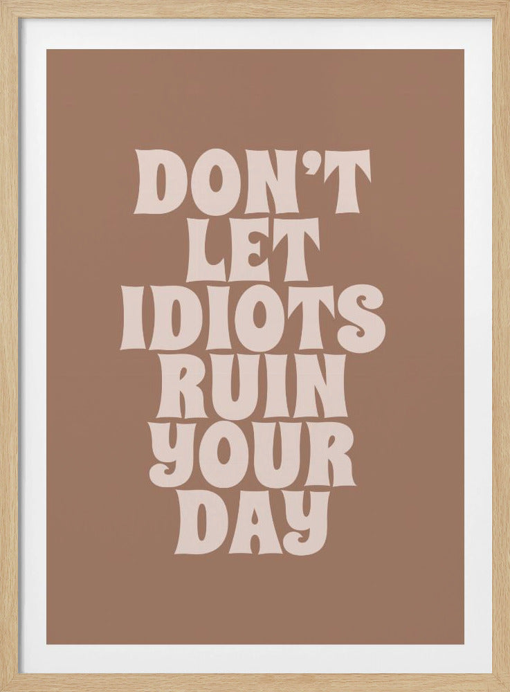 A retro-style poster featuring the quote 'DON'T LET IDIOTS RUIN YOUR DAY' in a bold, wavy, off-white font against a solid muted brown background, all within a simple black frame. Poster