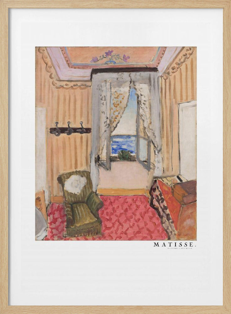 A framed print of a painting by Henri Matisse. The artwork depicts an interior room scene with peach-colored walls, a vibrant pink and red patterned rug, and an armchair. An open window with lace curtains offers a view of the blue sea. Decor