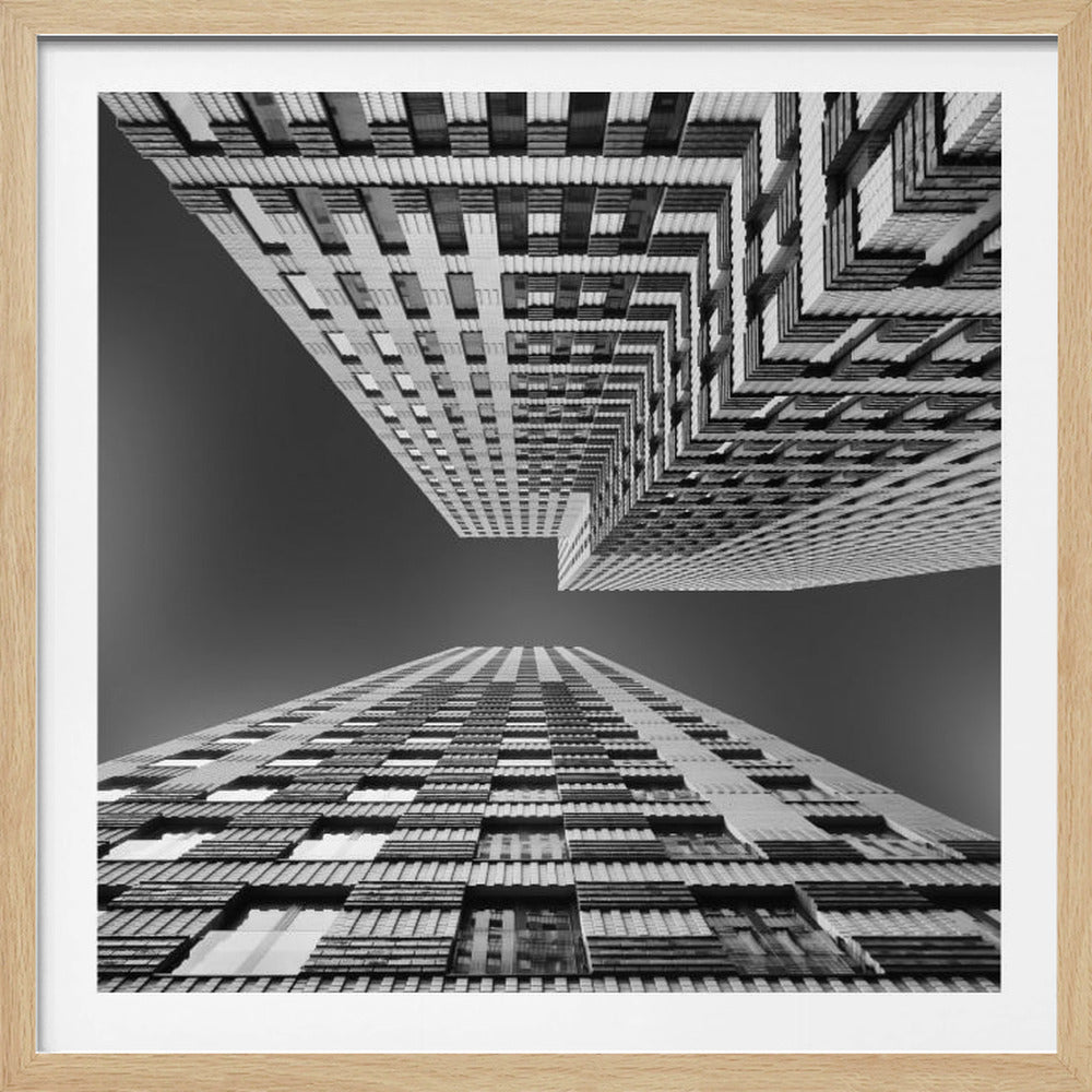A framed, black and white, low-angle photograph looking up between two towering skyscrapers, creating a dramatic perspective with geometric patterns against a dark sky. Poster