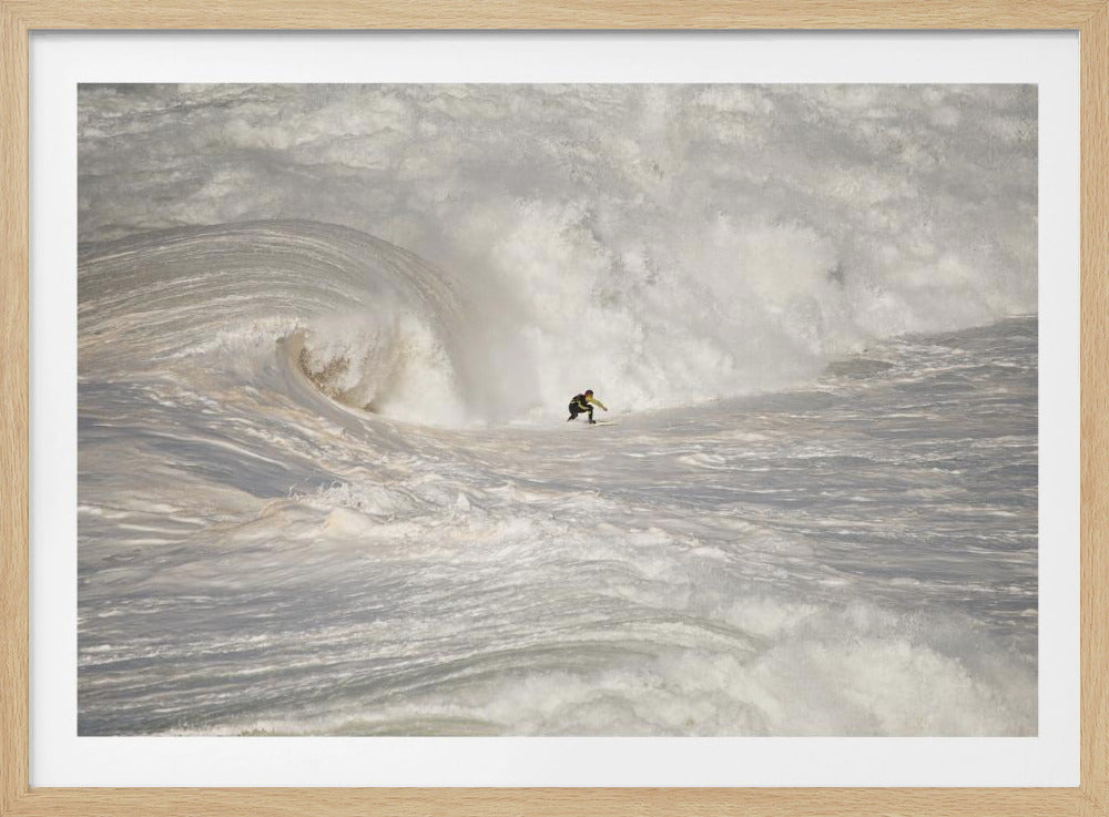 A framed photograph of a lone surfer dwarfed by a massive, powerful ocean wave. The water is a churning mass of white foam and spray, and the surfer is navigating the enormous swell. Print
