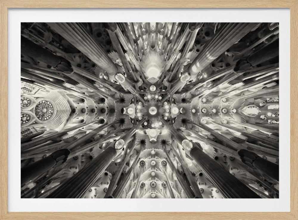 A framed black and white photograph captures the breathtaking, symmetrical ceiling of Gaudí's Sagrada Familia basilica, viewed directly from below. The massive columns rise and branch out like a forest canopy, creating a complex and mesmerizing architectural pattern of vaults, ribs, and skylights. Artwork