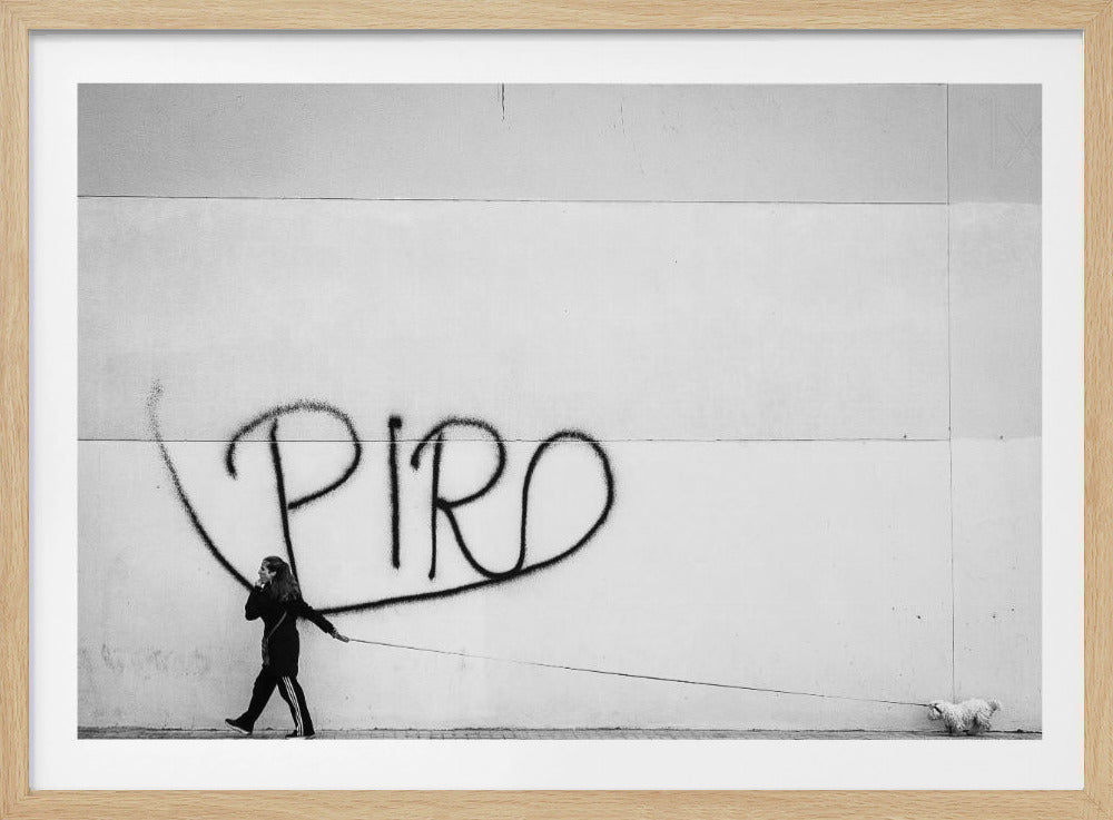 A minimalist black and white photograph of a woman dressed in black walking a small, fluffy white dog on a long leash. They are walking along a sidewalk in front of a large, pale wall with the word 'PIRO' written in black spray paint graffiti. The entire image is enclosed in a light grey frame. Poster