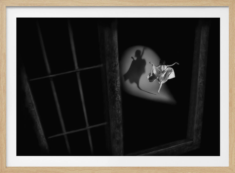 A dramatic black and white photograph viewed through a window frame. In a spotlight against a black background, a woman in a light dress dances gracefully, seen from behind. Her shadow cast on the wall is of a caped figure holding a sword, suggesting hidden strength or a heroic identity. Print
